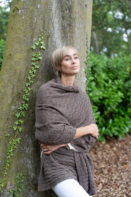 model wearing an alpaca wrap leaning on a tree