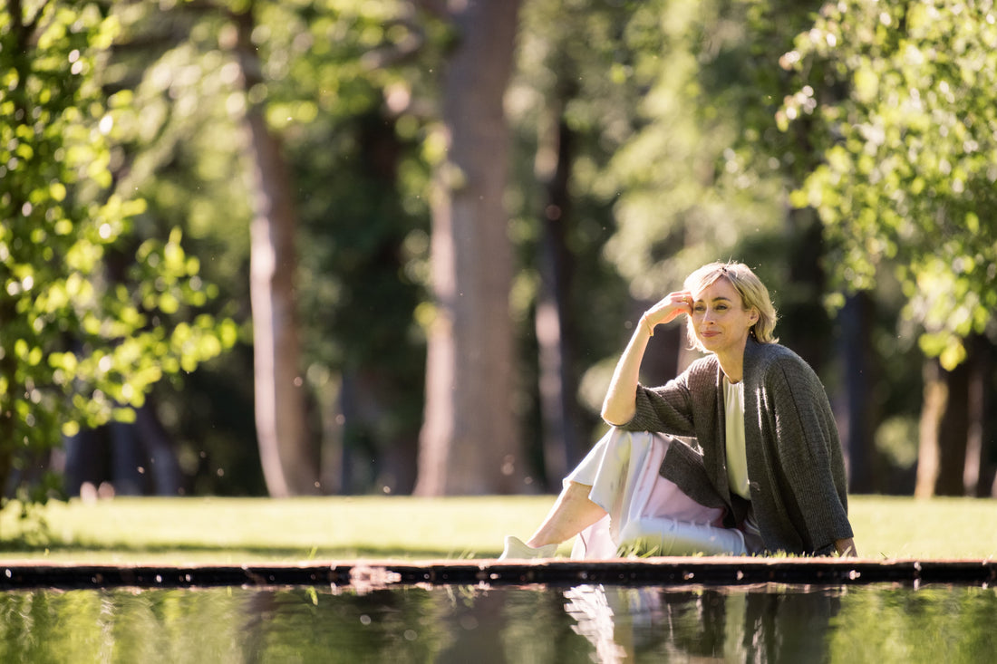 woman wearing an alpaca cardigan sitting by a pond