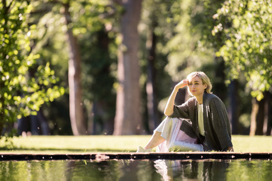 woman wearing an alpaca cardigan sitting by a pond