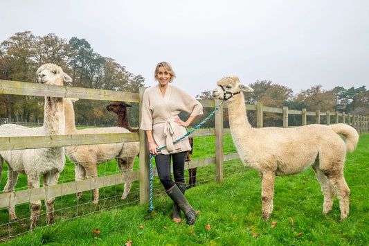 woman wearing an alpaca cardigan holding an alpaca