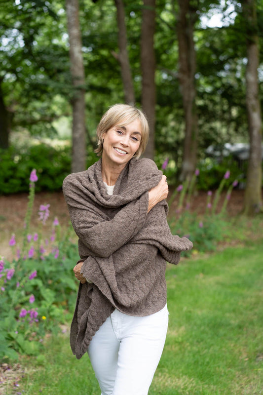 a woman wearing a alpaca wrap in a garden looking happy