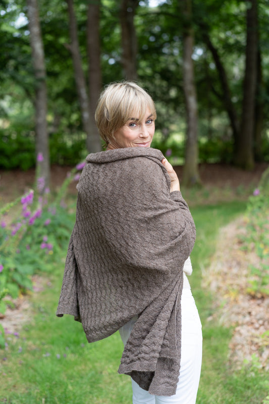 model wearing textured mid brown alpaca wrap in a garden